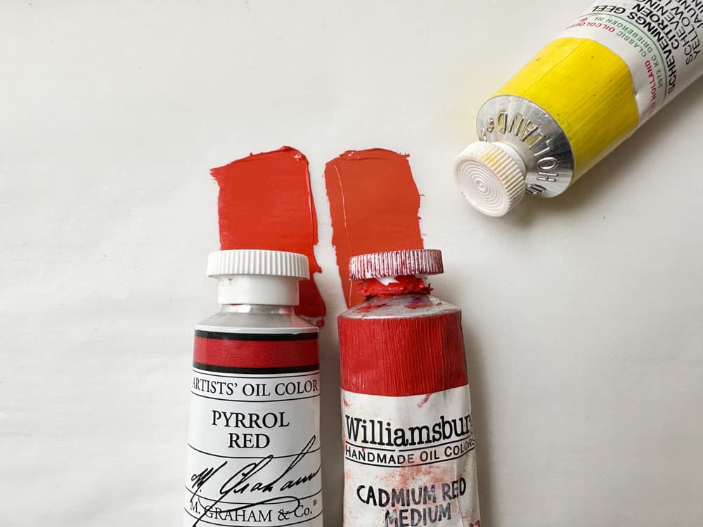 Two swatches of paint show mixes of M Graham Pyrrole Red with Scheveningen Yellow Lemon vs Williamsburg Cadmium Red Medium with Scheveningen Yellow Lemon. The Cadmium Red warmed a bit more readily and was perhaps a bit lower chroma while it seemed the Pyrrole retained a pinker quality.