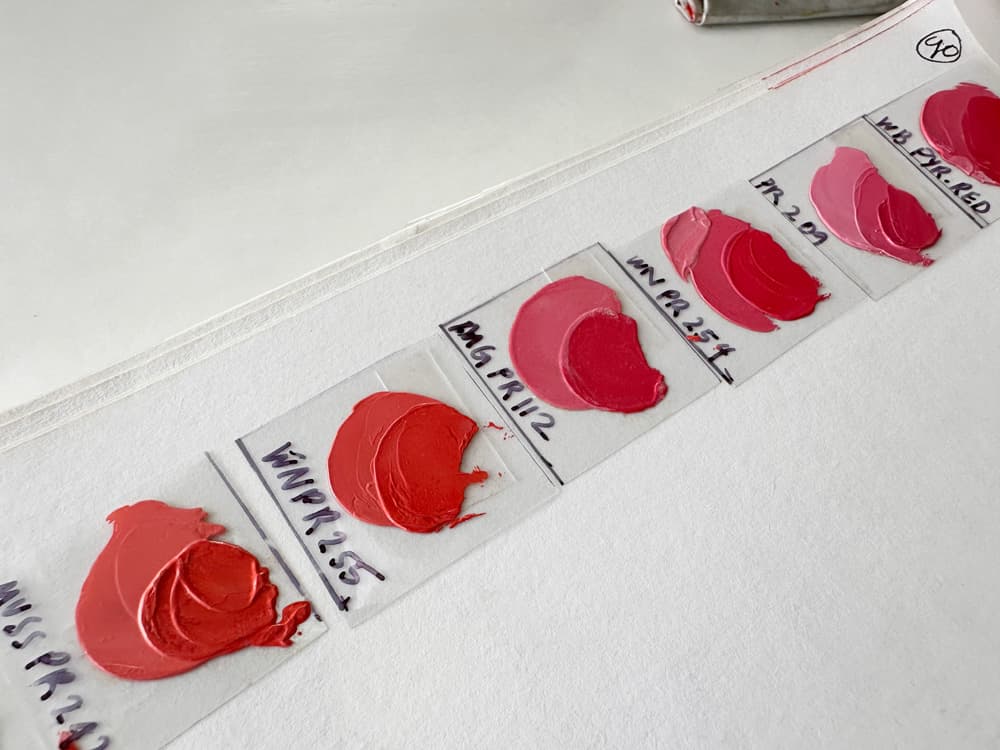A series of circular pigment swatches show the progression from orangy red to cooler reds.