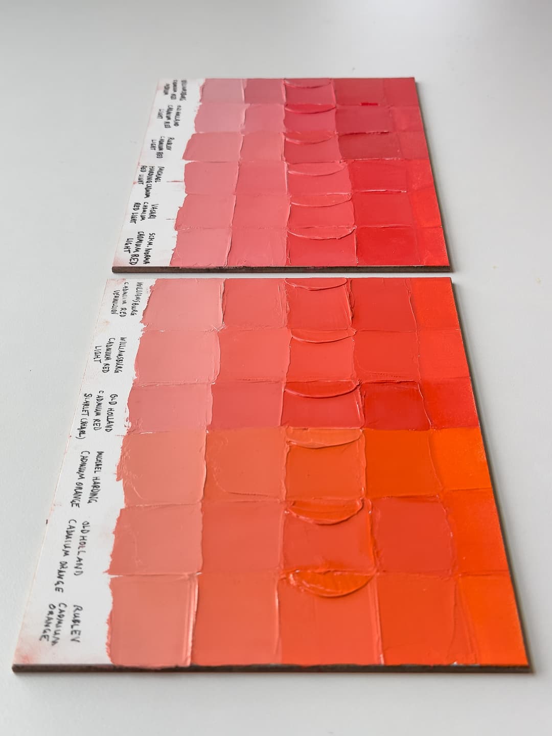 A variety of Cadmium Red Lights and Cadmium Orange in oil paints. Handpainted swatches made with a palette knife show the differences between paint brands