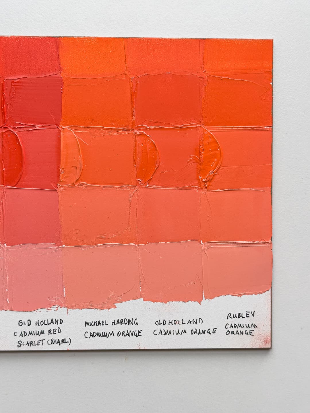 A panel with painted swatches of three red-leaning cadmium oranges.