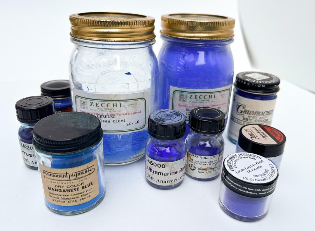 Jars of blue artists pigments showing genuine Manganese Blue, genuine Cerulean Blue, Ultramarine Blue, Genuine Lapis Lazuli, Genuine Cobalt Blue, and Prussian Blue