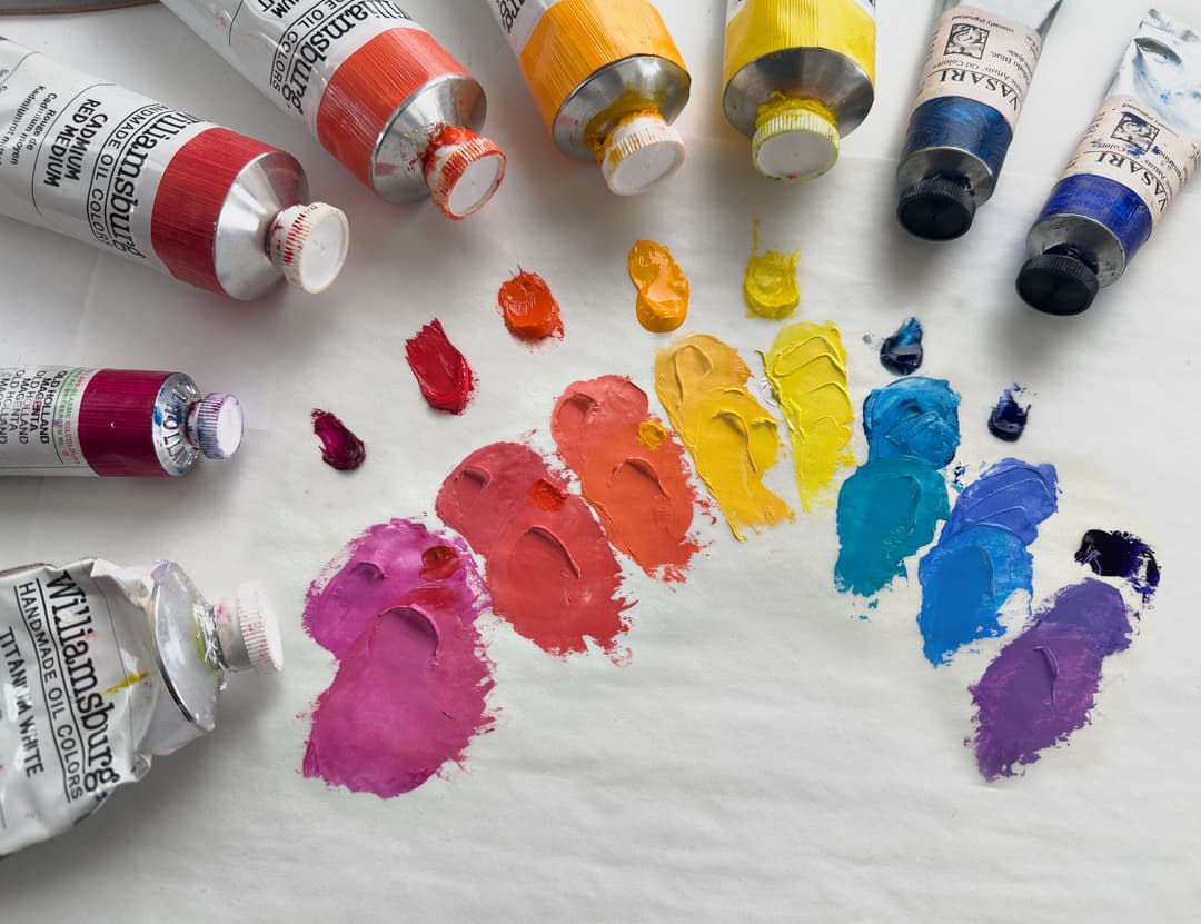 One strategy of how to warm up mixes of oil paint so that Titanium White does not look so cool and chalky. Dots of paint showing a color mixed with Titanium compared to that same blend with a touch of the adjacent color mixed in.