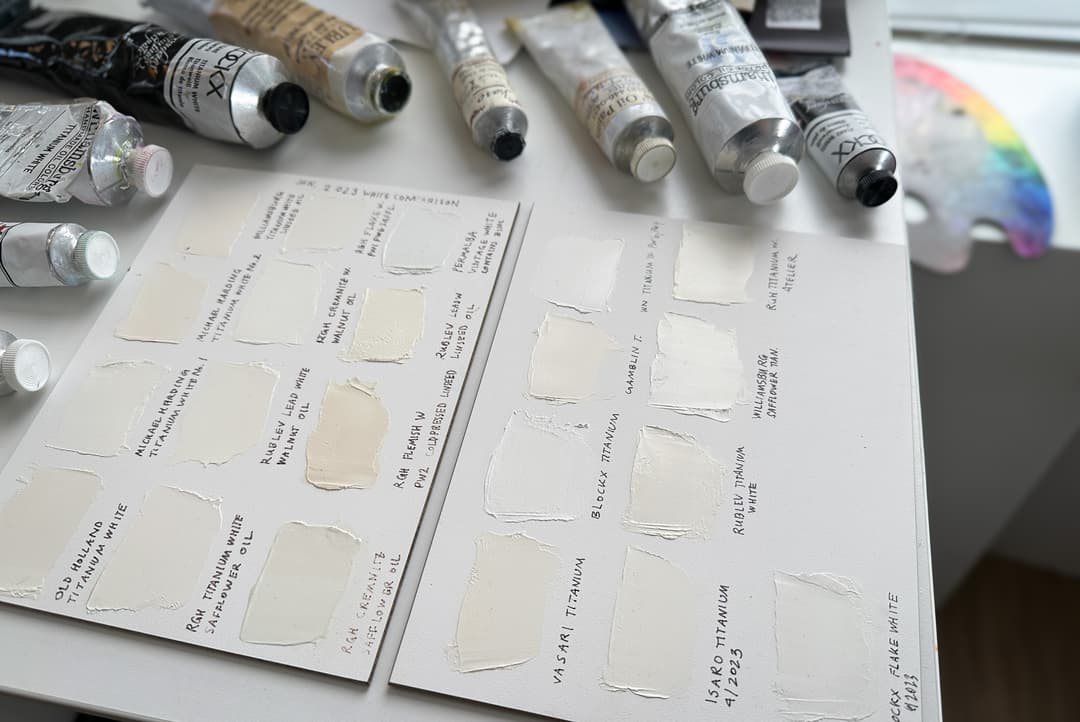Swatches of titanium white, lead white, and blends on a panel surrounded by paints.